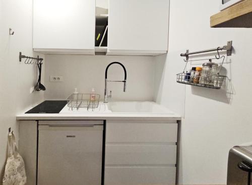 une cuisine avec des armoires blanches et un évier dans l'établissement Studio petit LU, à Nantes