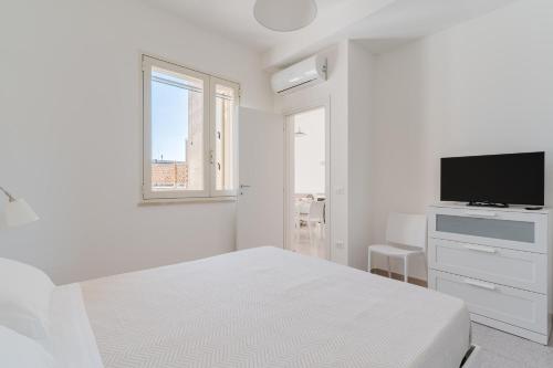 纳尔多Salento Vibes Apartments - Salento Selection的一间带床和平板电视的白色卧室