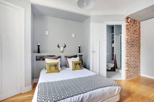 une chambre avec un grand lit avec des oreillers jaunes dans l'établissement Elegant 2 pièces moderne - rue du Colisée, à Paris