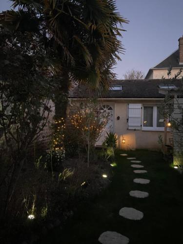 een huis met een palmboom en verlichting in de tuin bij Maisonnette individuelle au coeur de Vernon in Vernon