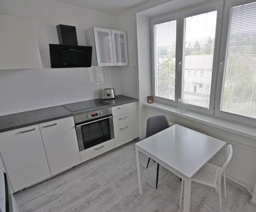 a kitchen with white cabinets and a table and a white table and chairs at UB private room in Bratislava in Bratislava