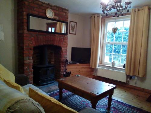 a living room with a brick fireplace and a coffee table at Valentine Cottage, Aylsham in Aylsham