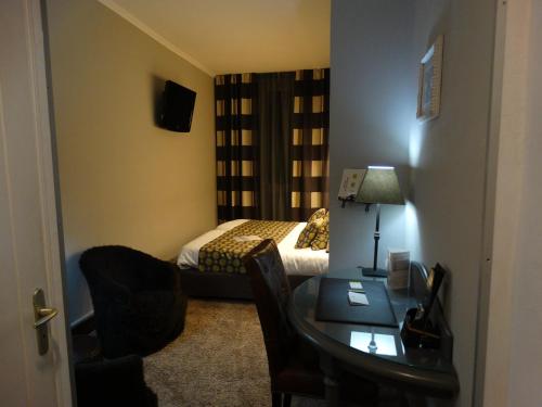 a small room with a bed and a desk with a table sidx sidx at Logis Hôtel Le Glacier in Orange
