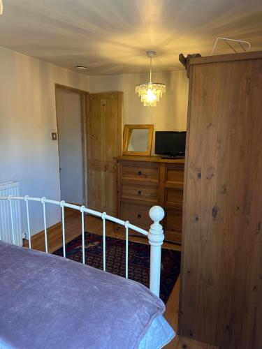 a bedroom with a bed and a dresser and a television at Valentine Cottage, Aylsham in Aylsham