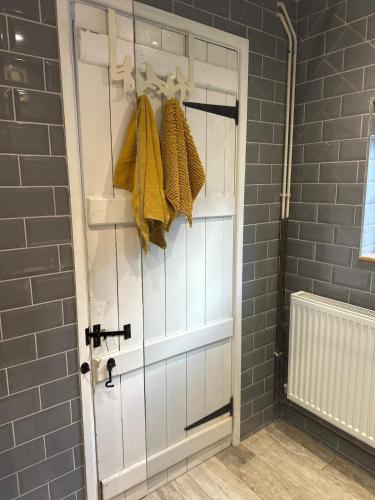 a bathroom with a white door with yellow towels at Valentine Cottage, Aylsham in Aylsham