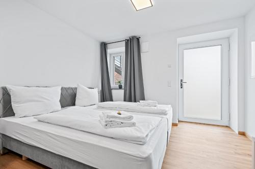 a white bedroom with a bed with towels on it at Stilvolles Apartment Bodensee A2 in Ravensburg