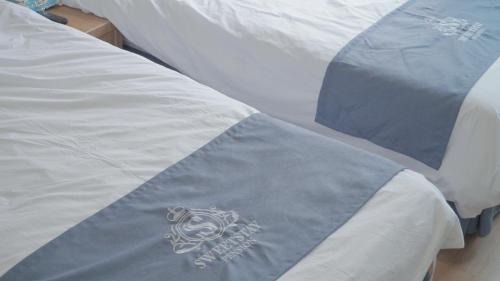 a bed with a blue blanket on top of it at Sweet Stay Pension in Seogwipo