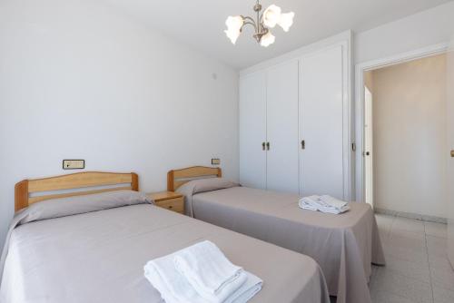 Dos camas en una habitación con paredes blancas. en Rentalmar Amanecer, en Miami Platja