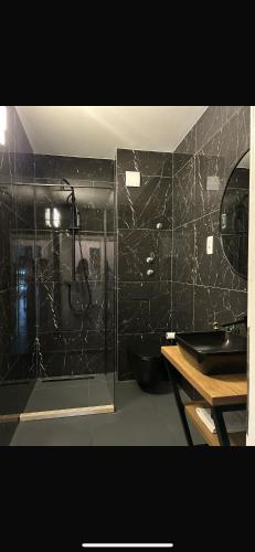 a bathroom with a shower with a black tiled wall at AAA Luxury Suites Split in Split