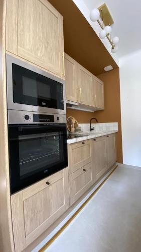 - une cuisine avec des placards en bois et un four micro-ondes dans l'établissement Le Darcy Bis - Entre Gare et Ville, à Dijon