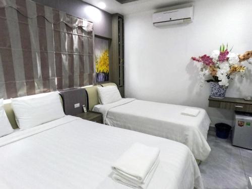 a hotel room with two beds and a vase of flowers at Vang Vieng Rivercube Hotel in Vang Vieng