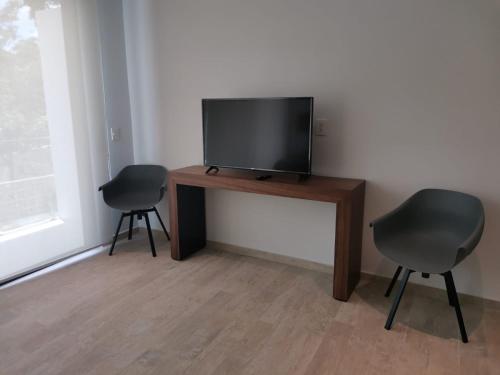 a room with two chairs and a television on a table at Central park lagunas in Tulum