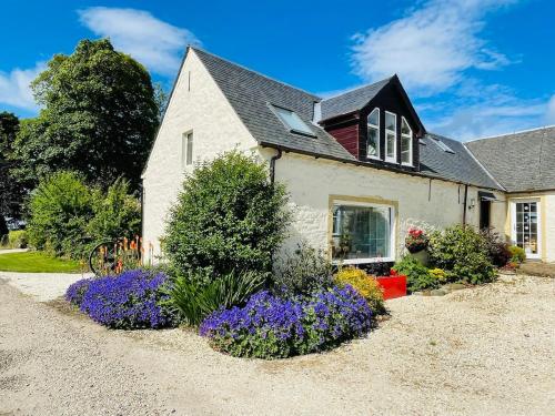 a house with flowers in the front yard at Stunning Barn Conversion in Dunlop
