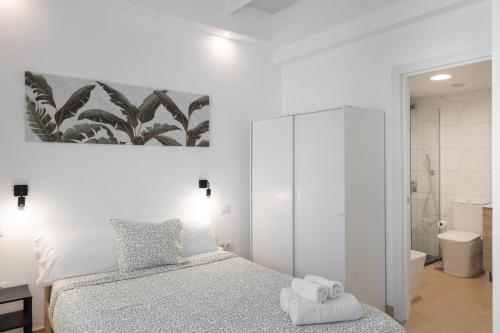 a white bedroom with a bed and a bathroom at Garden Terrace House - La Isleta in Guanarteme