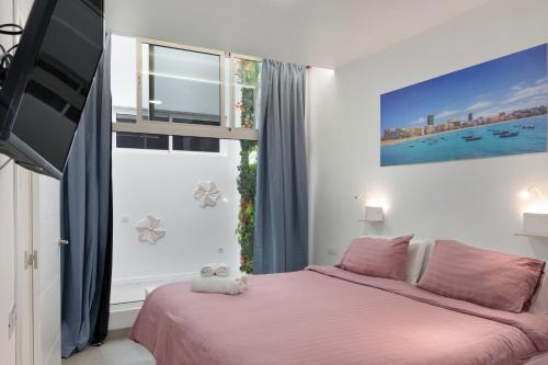 a bedroom with a pink bed and a window at Garden Terrace House - La Isleta in Guanarteme
