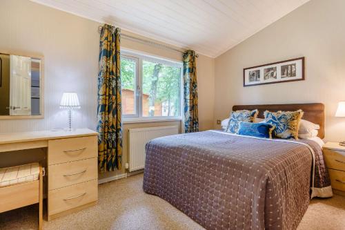 a bedroom with a bed and a desk and a window at Duet Lodge in Kingham