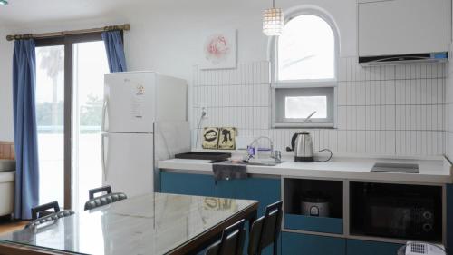 a white kitchen with a sink and a refrigerator at Sweet Stay Pension in Seogwipo
