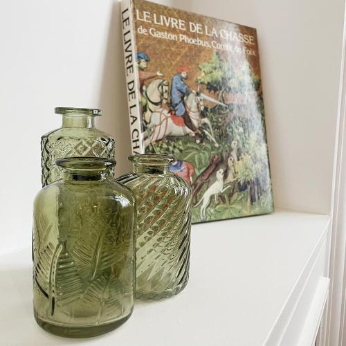 two glass vases sitting on a shelf next to a painting at Le jardin de L'Hippodrome in Chantilly