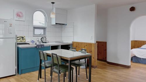 a kitchen with a table and chairs and a bed at Sweet Stay Pension in Seogwipo