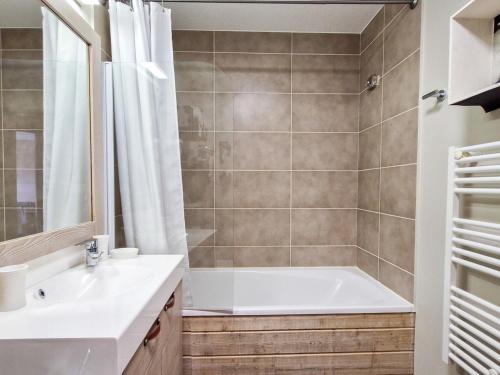 une salle de bain avec une baignoire et un lavabo dans l'établissement Appartement 2 pièces skis aux pieds avec piscine et spa - FR-1-425-232, à Arâches-la-Frasse