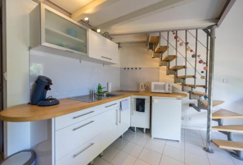 une cuisine avec des placards blancs et un escalier en colimaçon dans l'établissement Appartement L'écrin de Lumière - Résidence Kiwi, à Aytré