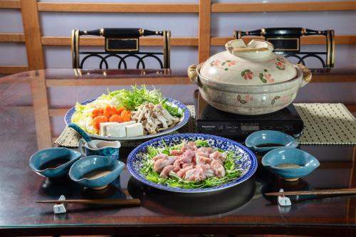 a table with two bowls of food and a pot at Villa璃都りーと Villa Retreat in Ibaraki