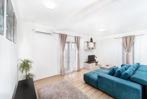 a living room with a blue couch and a tv at Apartament nou de 3,Stele Maria Parking free in Giroc