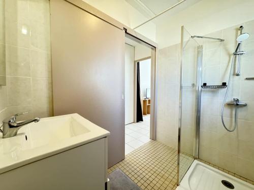 une salle de bain avec un lavabo et une douche dans l'établissement Appartement Les vagues dorées - Résidence Kiwi, à Aytré