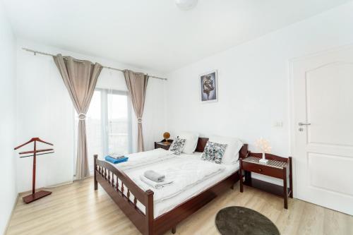 a white bedroom with a bed and a window at Apartament nou de 3,Stele Maria Parking free in Giroc