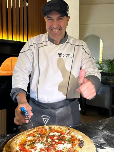 a man is holding up a plate of pizza at Villa Caruso in Massa Lubrense