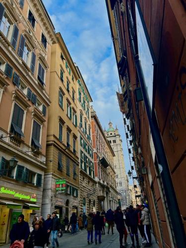 a group of people walking down a street with buildings at A un passo da in Genova
