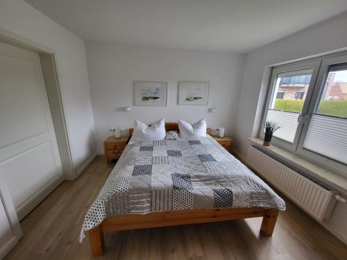 a bedroom with a bed with a comforter and two windows at Ferienwohnung Stiena EG in Greetsiel