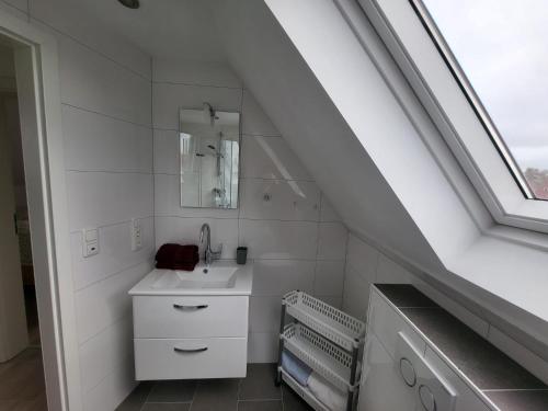 a white bathroom with a sink and a window at Ferienwohnung Stiena EG in Greetsiel