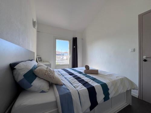 a bedroom with a bed with a blue and white blanket at Sunset Aparthotel Kiwi Residence in Aytré