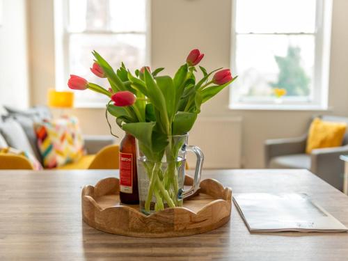a vase with red tulips sitting on a table at Pass the Keys Modern and Airy Apartment in heart of Wellington in Wellington