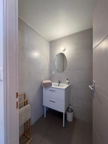 a white bathroom with a sink and a mirror at Sunset Aparthotel Kiwi Residence in Aytré