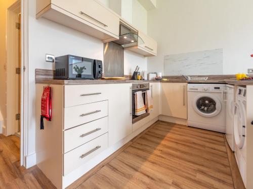 a kitchen with white cabinets and a washer and dryer at Pass the Keys Modern and Airy Apartment in heart of Wellington in Wellington