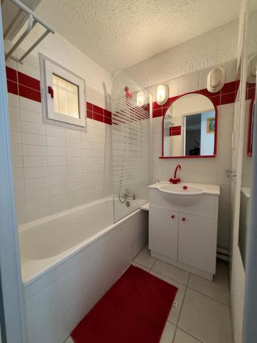 une salle de bain avec une baignoire blanche, un lavabo et un miroir dans l'établissement Superbe T2 à 10 min de la Mer, Piscine, Climatisation, Parking, au Lavandou