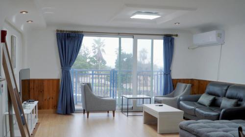 a living room with a couch and chairs and a large window at Sweet Stay Pension in Seogwipo
