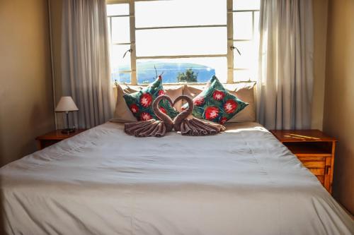 a bed with some pillows on top of it at Panorama Chalets & Rest Camp in Graskop