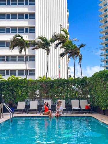 two women sitting on the edge of a swimming pool at Circa 39 Miami Beach in Miami Beach
