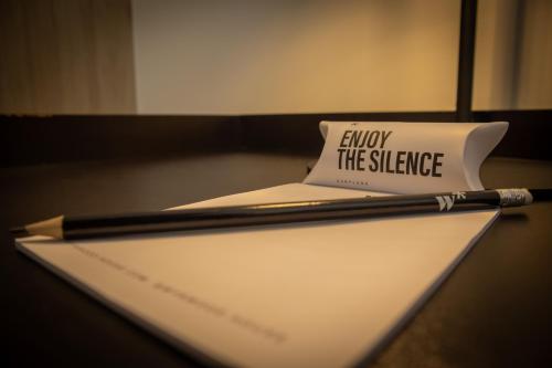 a pen sitting on top of a piece of paper with enjoy the silence sign at Pod by Wynwood House in Lima