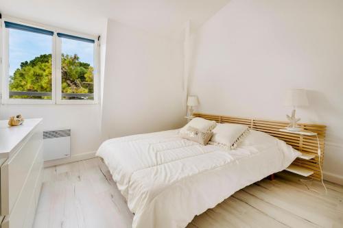 a white bedroom with a bed and a window at Le Joli Baulois in La Baule