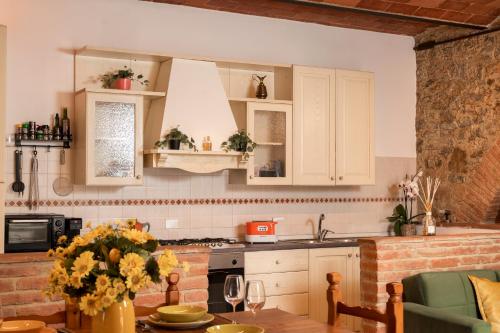 a kitchen with white cabinets and a table with flowers at Casa Nataly Chianti - Jeky Stay in Castelnuovo Berardenga