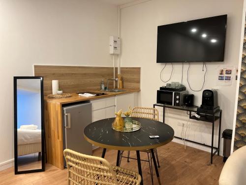 un salon avec une table et une télévision au mur dans l'établissement La Suite Secrète, à Amiens