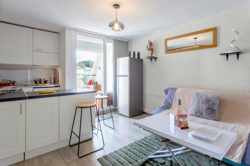 Il dispose d'une cuisine et d'un salon avec une table et un réfrigérateur. dans l'établissement Chez Hélène - Charmant deux pièces climatisé avec parking privé, à La Grande Motte
