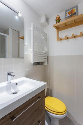 La salle de bains est pourvue de toilettes jaunes et d'un lavabo. dans l'établissement Chez Hélène - Charmant deux pièces climatisé avec parking privé, à La Grande Motte