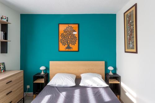 une chambre avec un mur bleu et un lit dans l'établissement Chez Hélène - Charmant deux pièces climatisé avec parking privé, à La Grande Motte