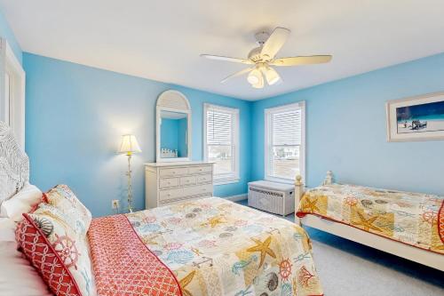 a blue bedroom with two beds and a ceiling fan at Heron's Retreat in Ocean City