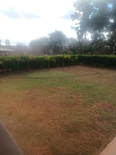a grassy yard with a fence in the background at Casa na fazenda inteira ou quartos individuais no Hostel Recanto da Felicidade Paraopeba in Paraopeba